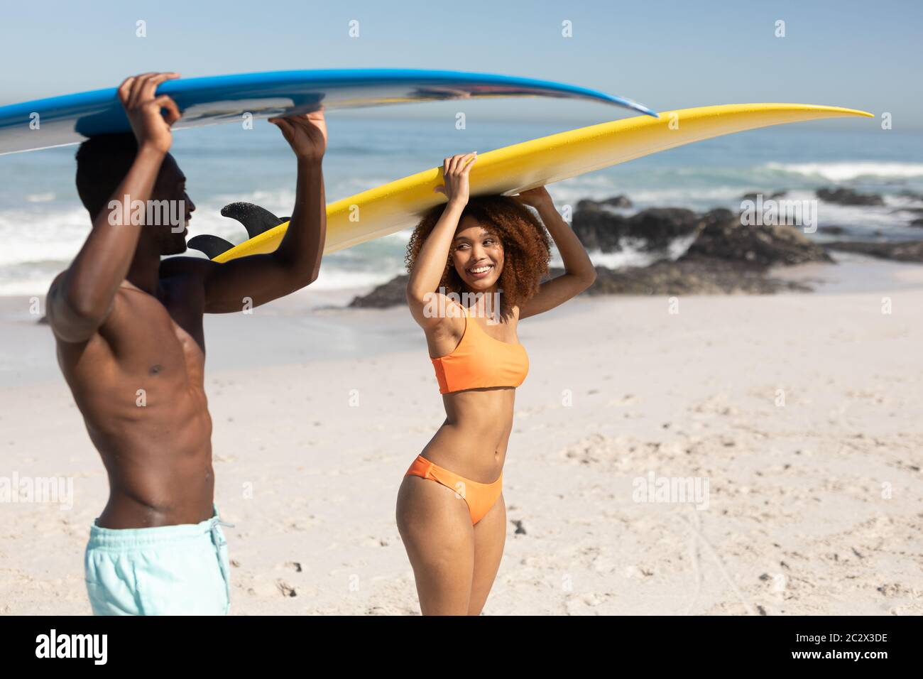 Gemischtes Rennpaar hält Surfbretter am Strand Stockfoto