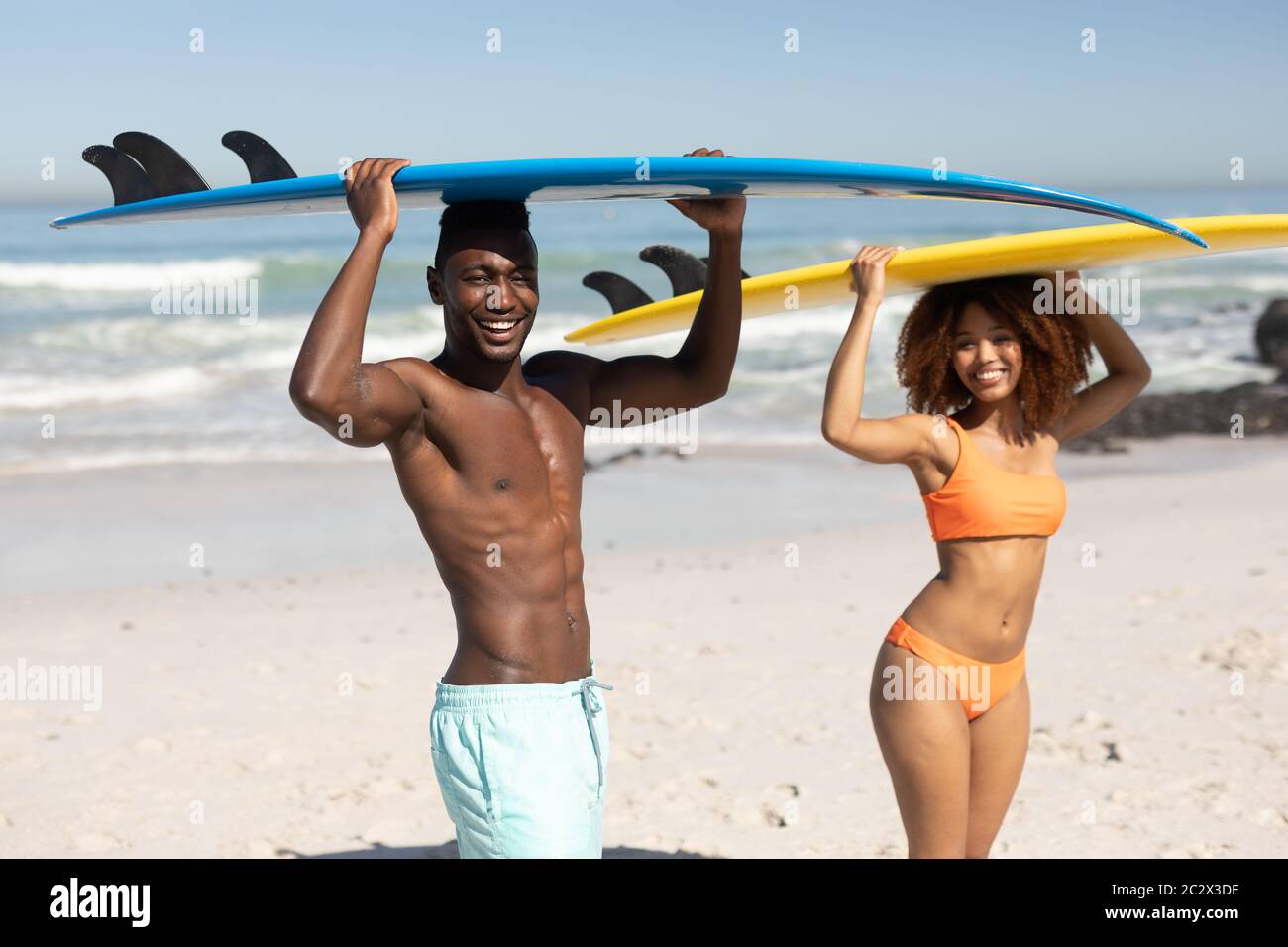 Gemischtes Rennpaar hält Surfbretter am Strand Stockfoto