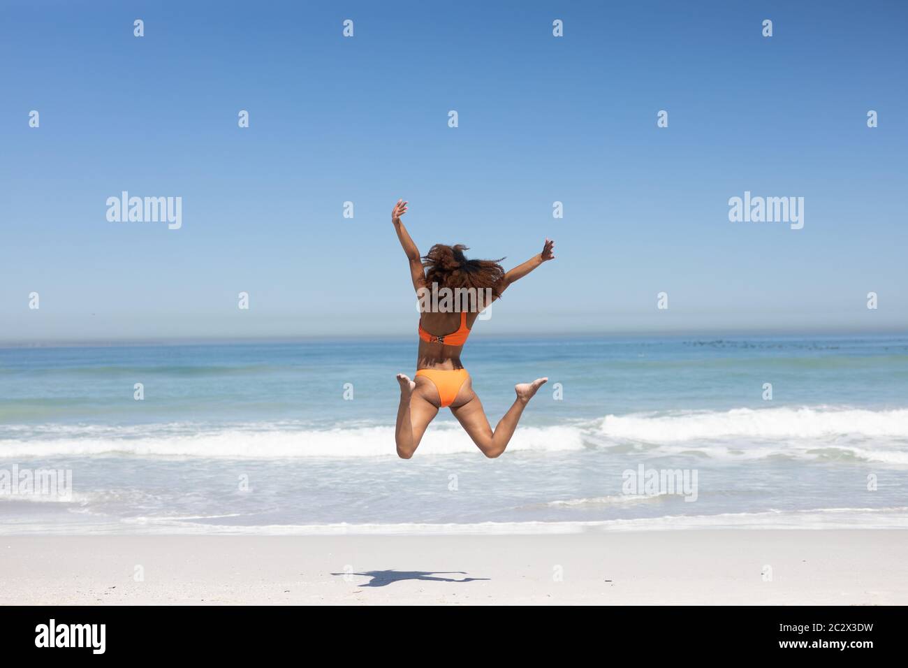 Mixed Race Frau springen am Strand Stockfoto