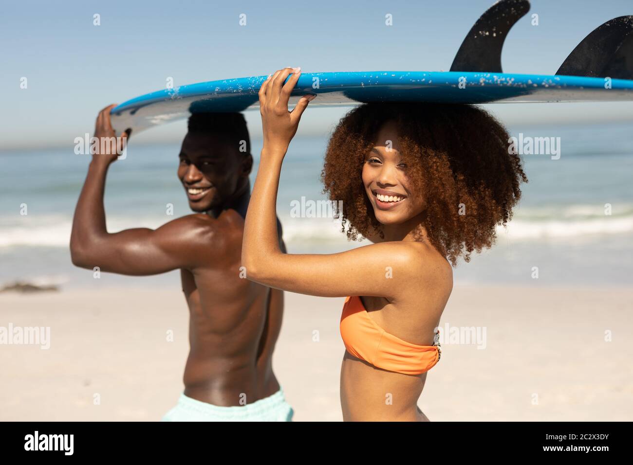 Gemischtes Rennpaar hält Surfbretter am Strand Stockfoto