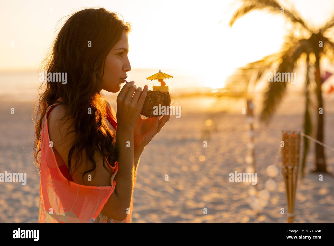 Junge Mischrennerin trinkt Cocktail am Strand Stockfoto