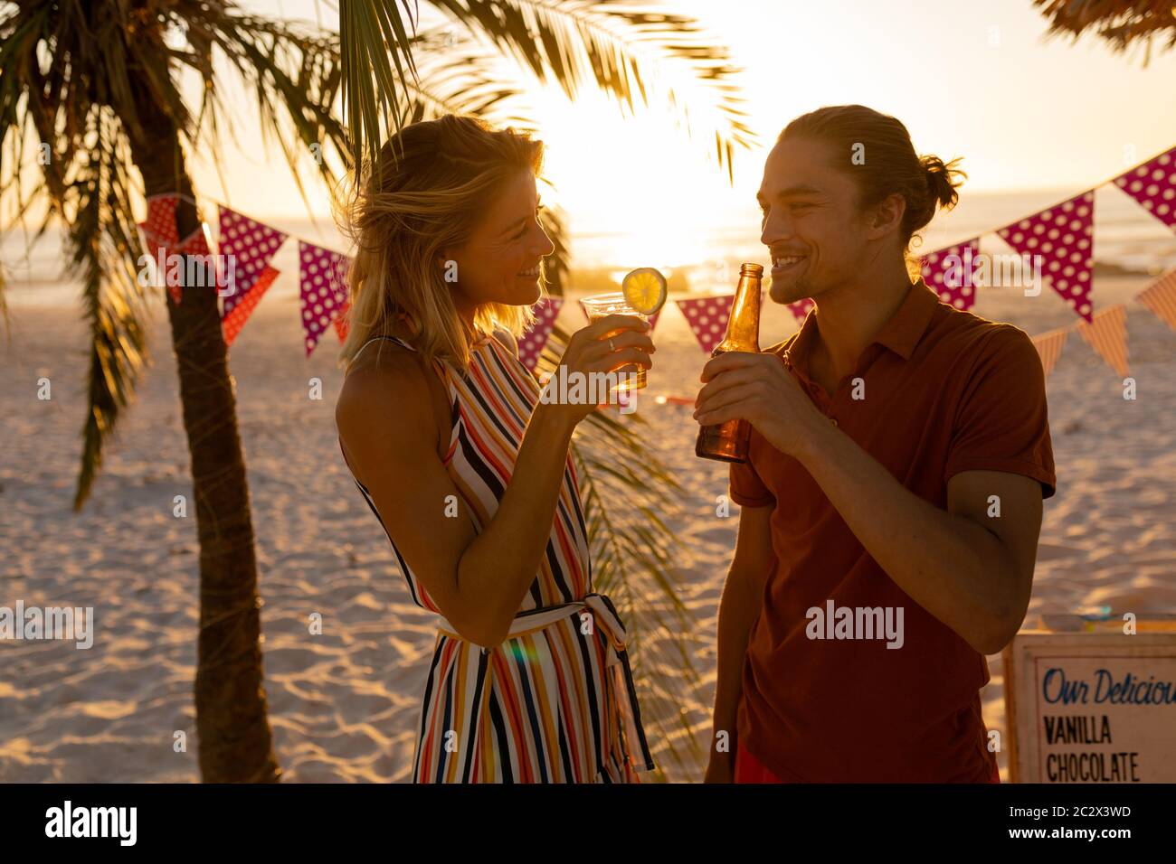 Kaukasisches Paar lächelt und trinkt Alkohol am Strand Stockfoto