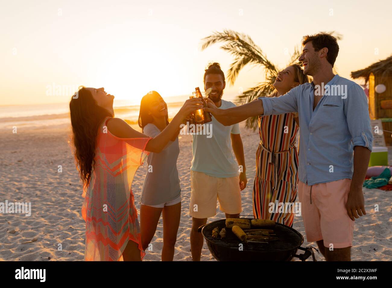 Gemischte Rennfreunde beim Grillen und Alkohol am Strand Stockfoto