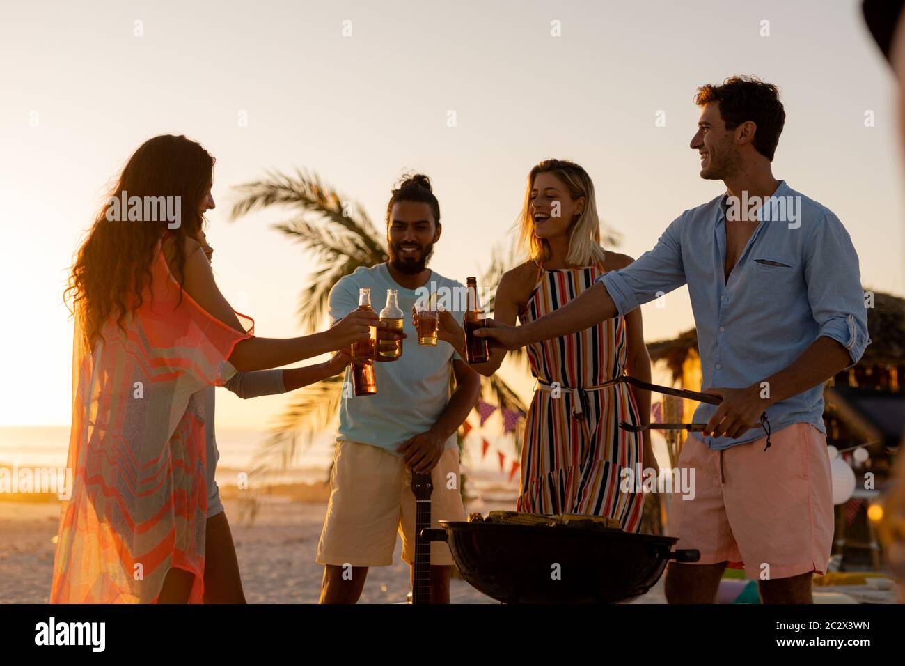 Gemischte Rennfreunde beim Grillen und Alkohol am Strand Stockfoto