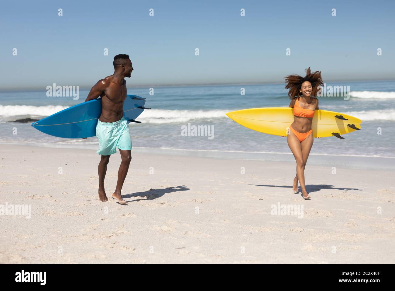 Glückliches Paar, das Surfbretter am Strand hält Stockfoto