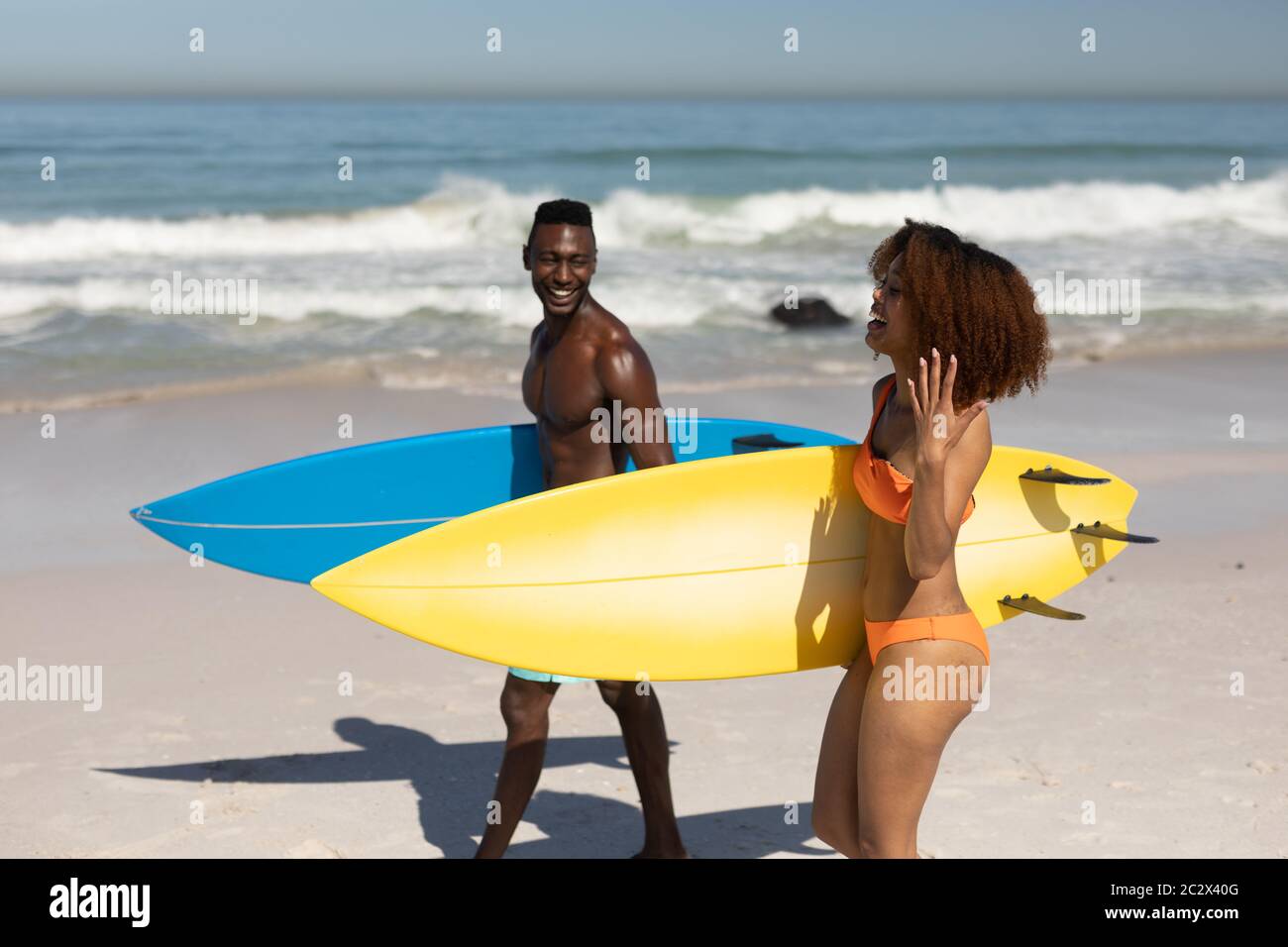 Glückliches Paar, das Surfbretter am Strand hält Stockfoto
