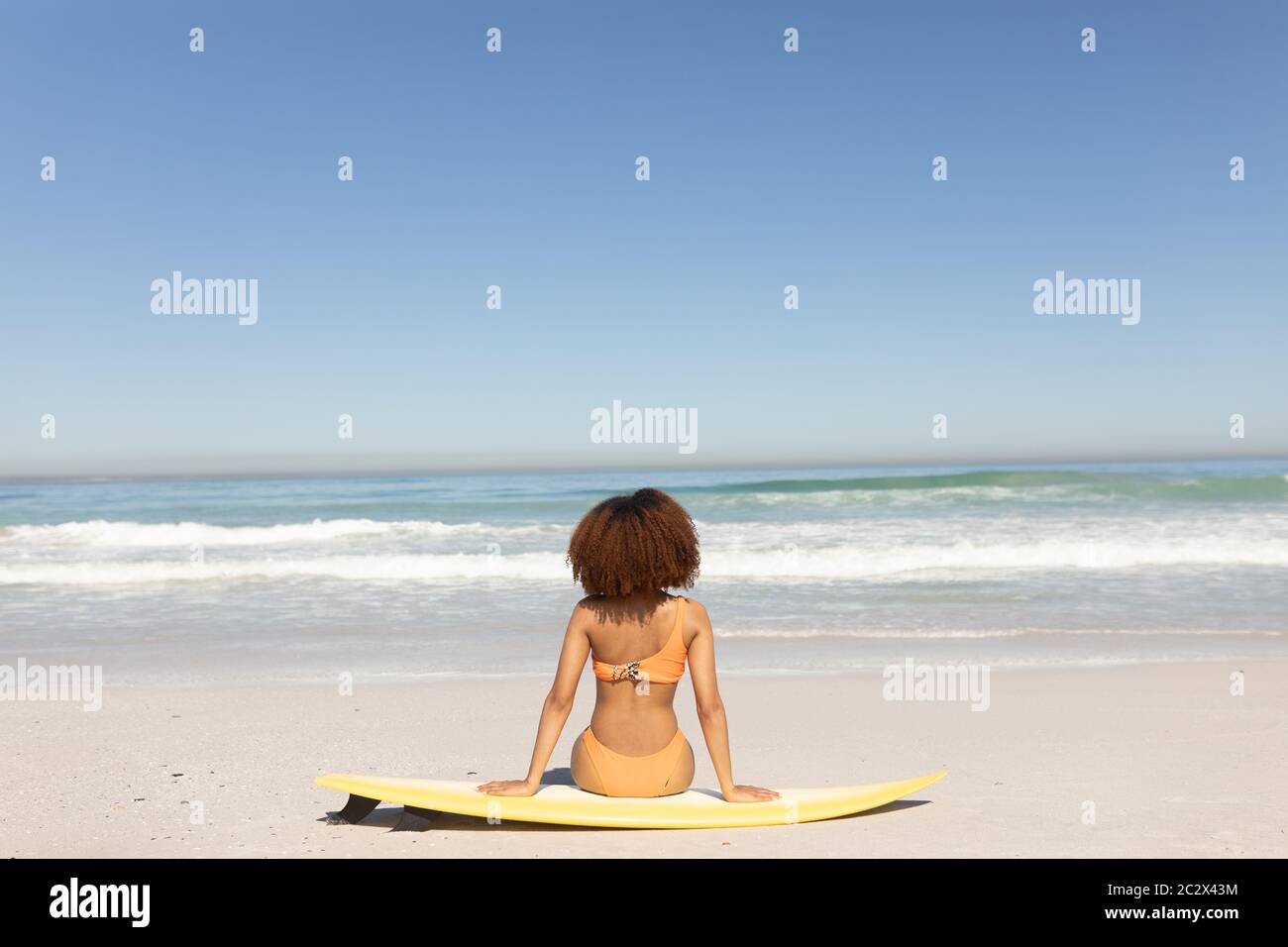 Mixed Race Frau sitzt am Strand Stockfoto