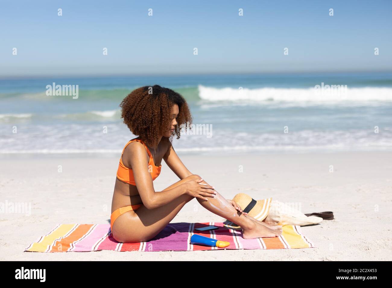 afroamerikanische Frau, die Sonnencreme am Strand legt Stockfoto