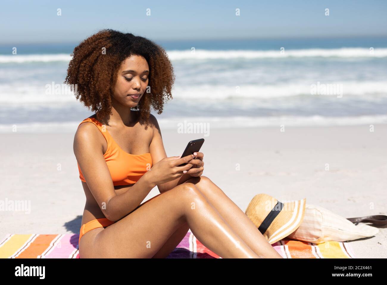 afroamerikanische Frau mit ihrem Smartphone am Strand Stockfoto