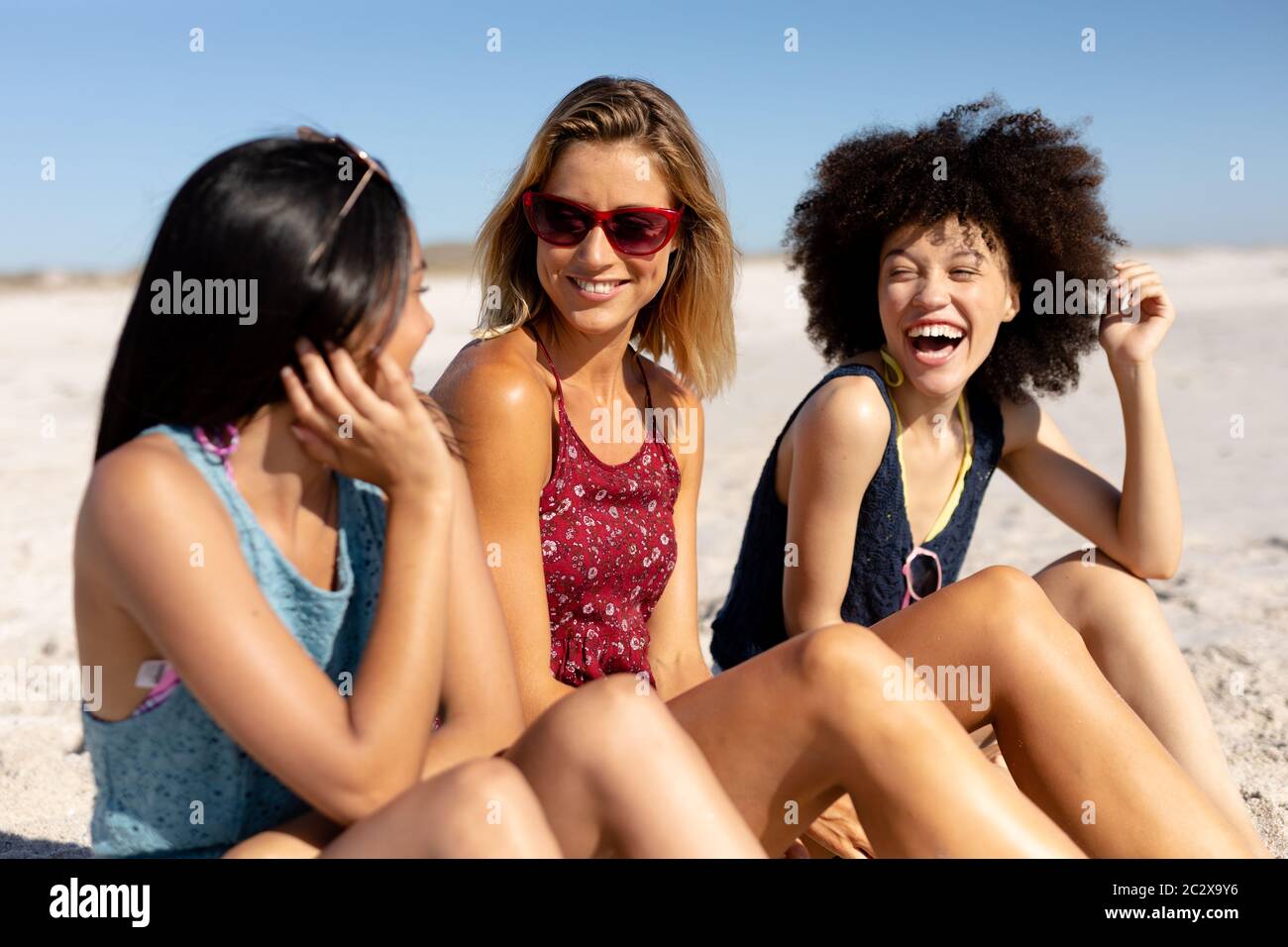 Multiethnische Gruppe von Frauen, die am Strand sitzen Stockfoto