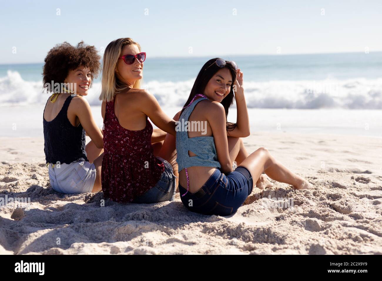 Multiethnische Gruppe von Frauen, die am Strand sitzen Stockfoto