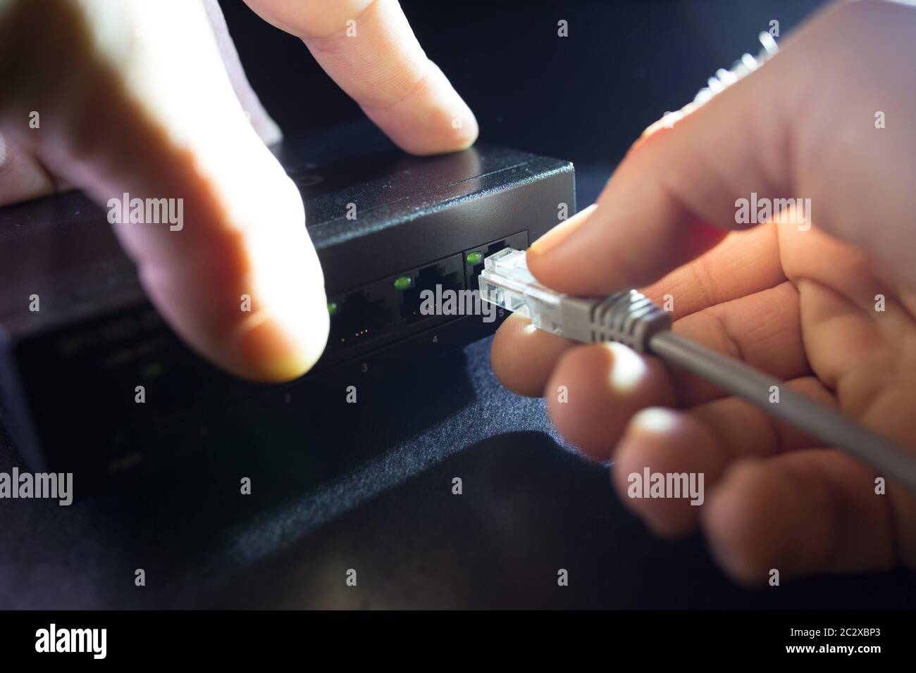 Close-up Hand Ethernet Kabel am Netzwerk Switches Hintergrund. Home Network Konzept. Stockfoto