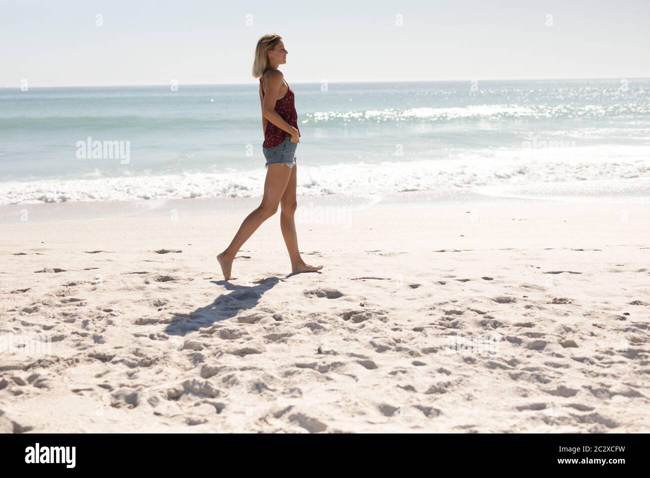 Junge kaukasische Frau zu Fuß am Strand Stockfoto