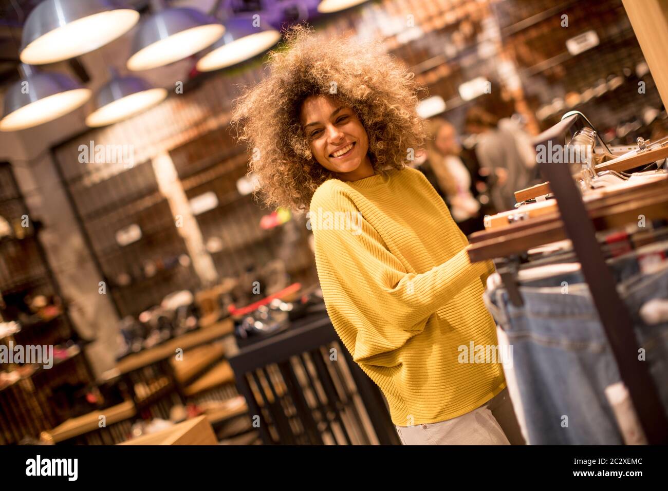 Hübsche junge schwarze Frau mit lockigem Haar in Shopping Stockfoto