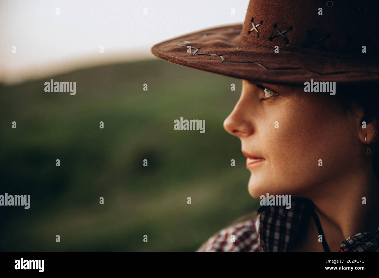 Mädchen im amerikanischen Country-Stil, Hemd und Cowboy-Hut in der Natur. Bei Sonnenuntergang Stockfoto