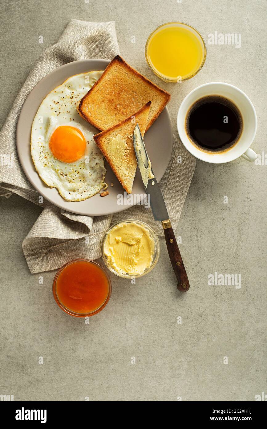 Frühstück serviert mit Spiegelei, Marmelade, Butter, Kaffee und Saft auf dem Tisch. Gesundes Frühstück essen Stockfoto