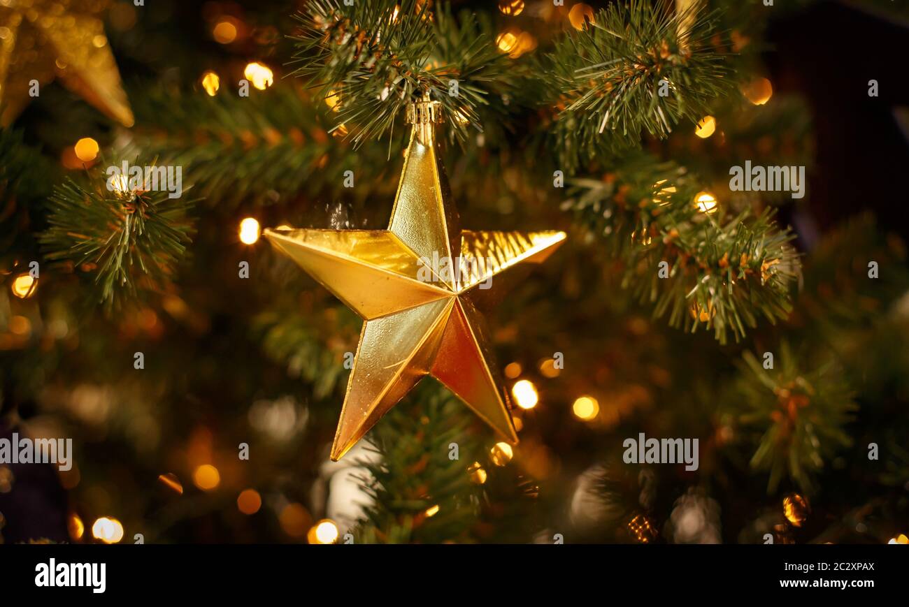 Weihnachtsbaum mit goldenen Kugeln Ornamente. Geschmückter Weihnachtsbaum aus der Nähe. Bälle und beleuchtete Girlande mit Taschenlampen. Neu Stockfoto