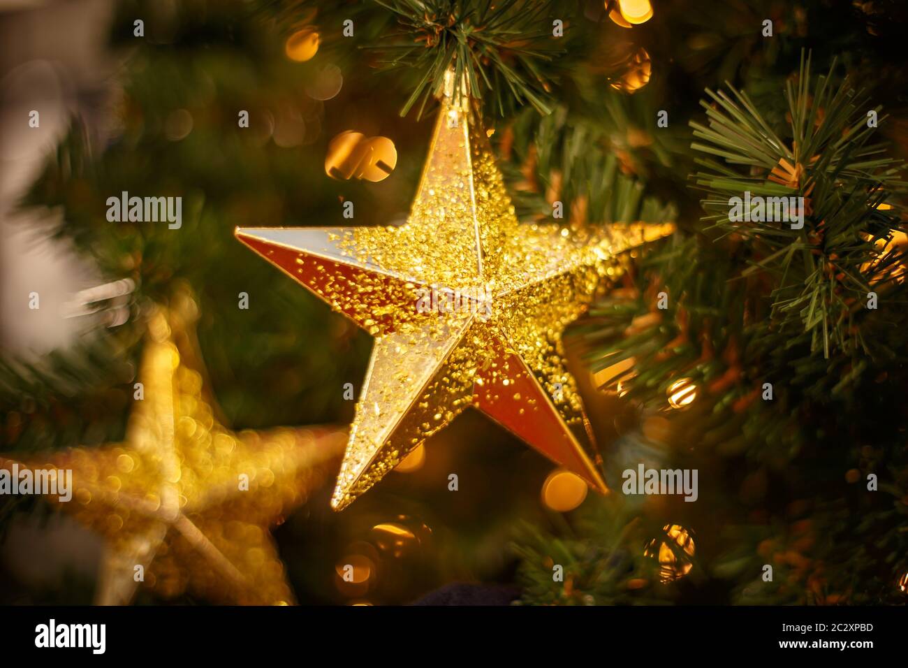 Weihnachtsbaum mit goldenen Kugeln Ornamente. Geschmückter Weihnachtsbaum aus der Nähe. Bälle und beleuchtete Girlande mit Taschenlampen. Neu Stockfoto