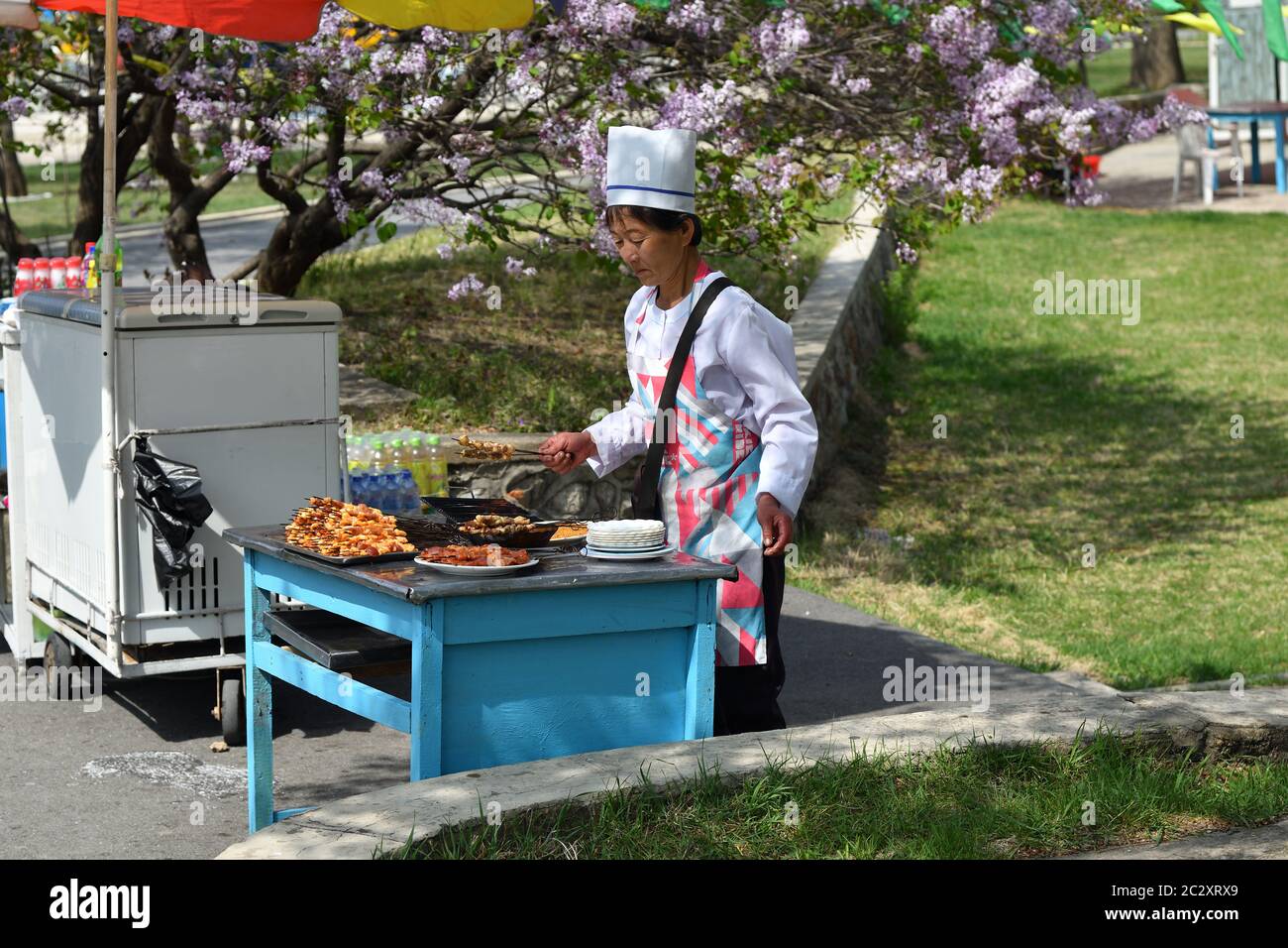 Pjöngjang, Nordkorea - 1. Mai 2019: Verkäuferin von gebratenem Fleisch auf dem Taesongsan-Jahrmarkt. Ist ein Vergnügungspark in Taesong-guyok Stockfoto