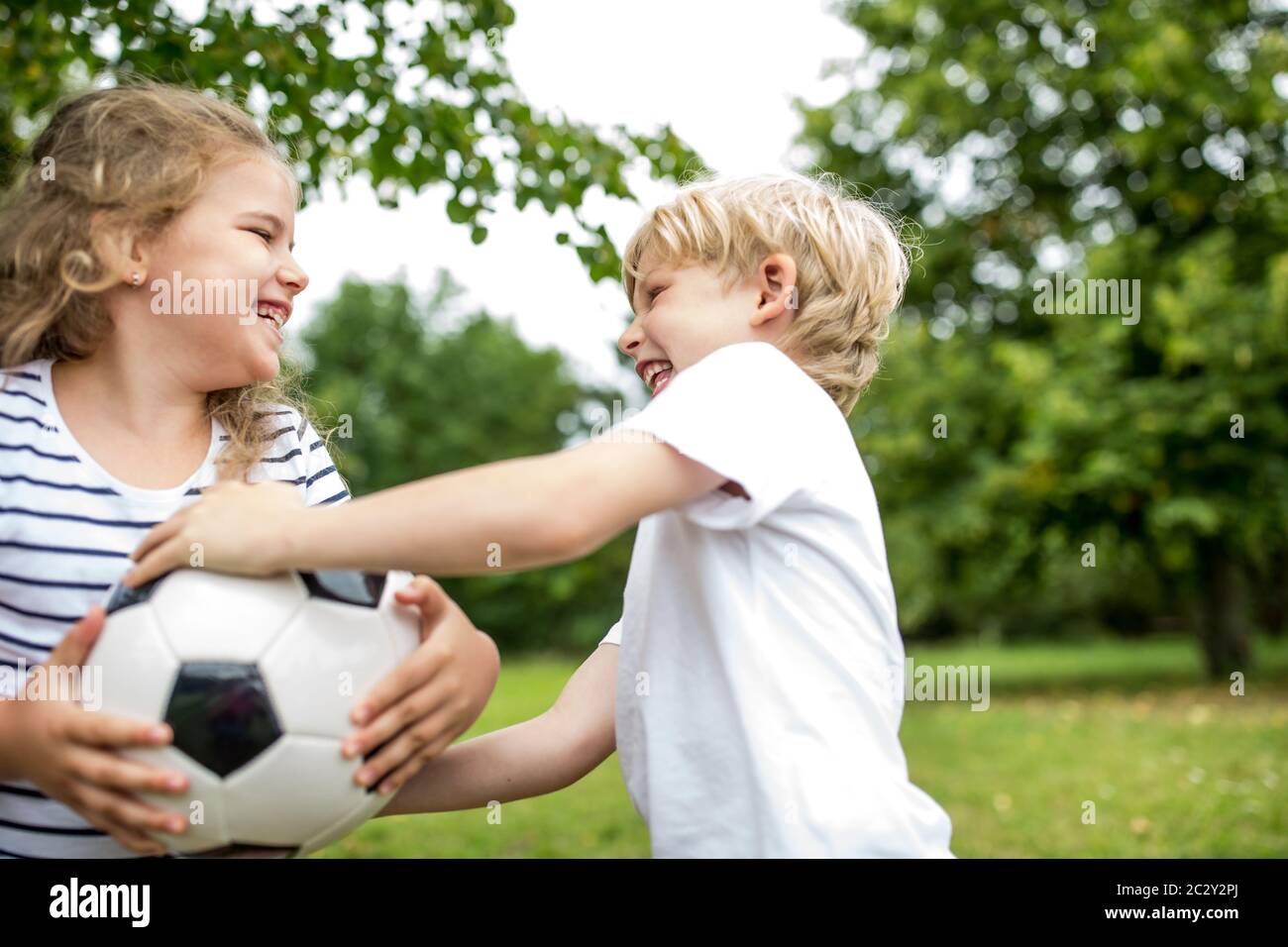 Im Sommer kämpfen zwei Kinder im Park um einen Ball Stockfoto