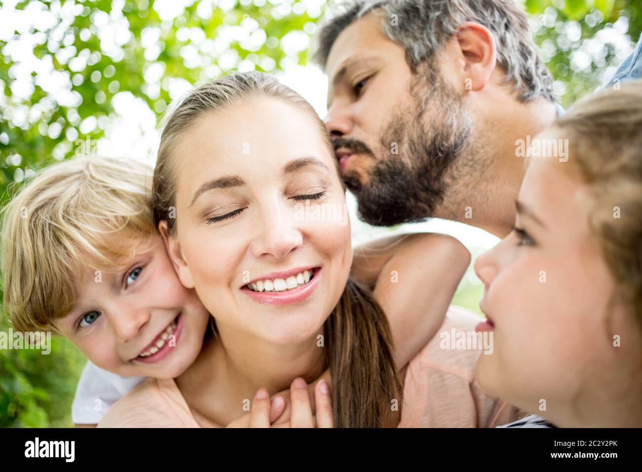 Glückliche Familie im Garten im Sommer mit Kind Huckepack auf Mutter Stockfoto