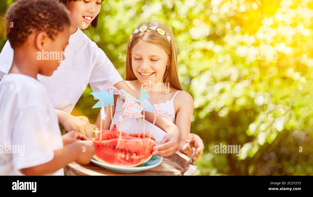 Drei Kinder teilen sich eine Wassermelone auf der Kindergeburtstag im Garten Stockfoto