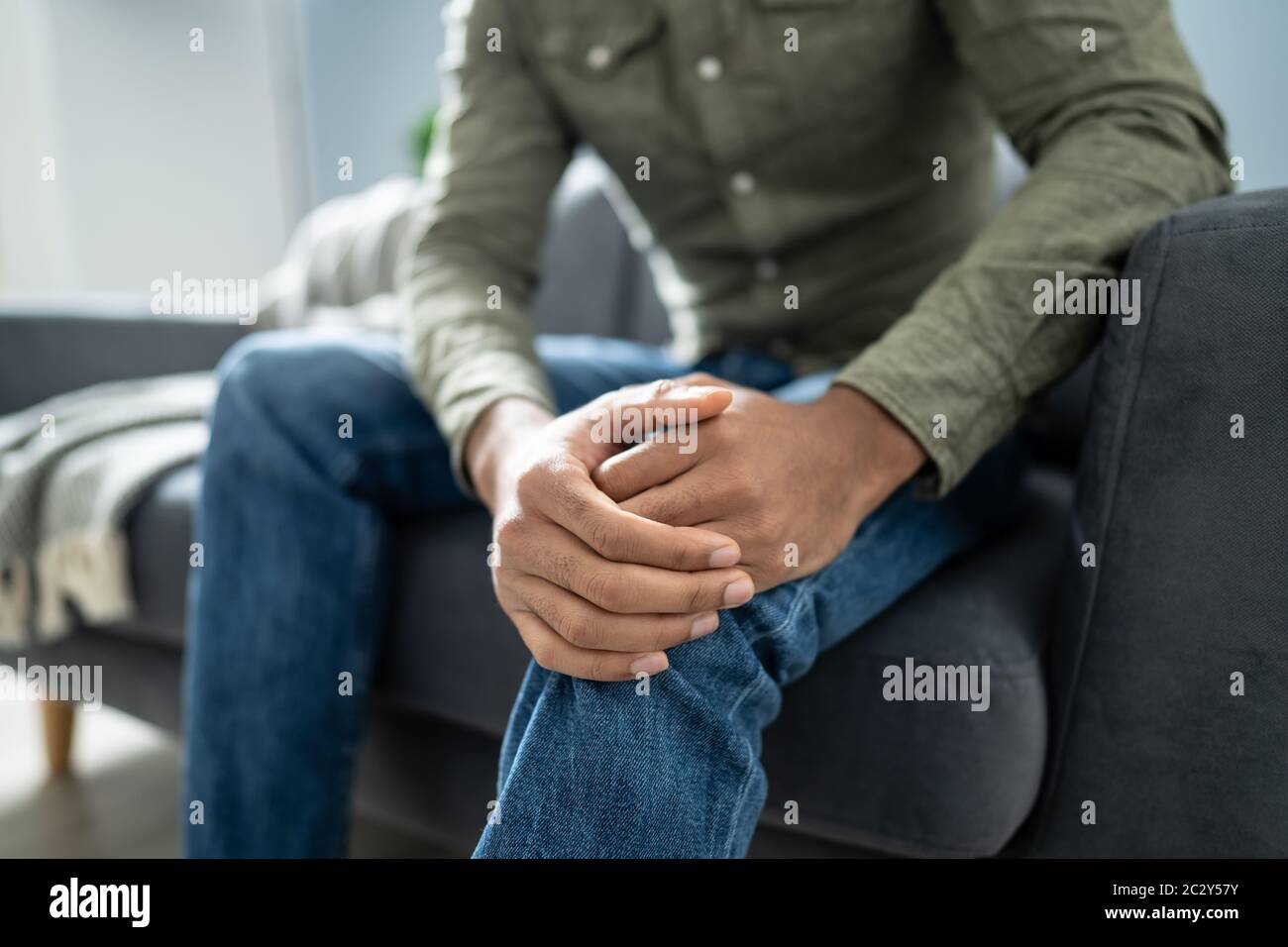 Menschen leiden unter Knieschmerzen Sitzen auf einem Sofa Stockfoto