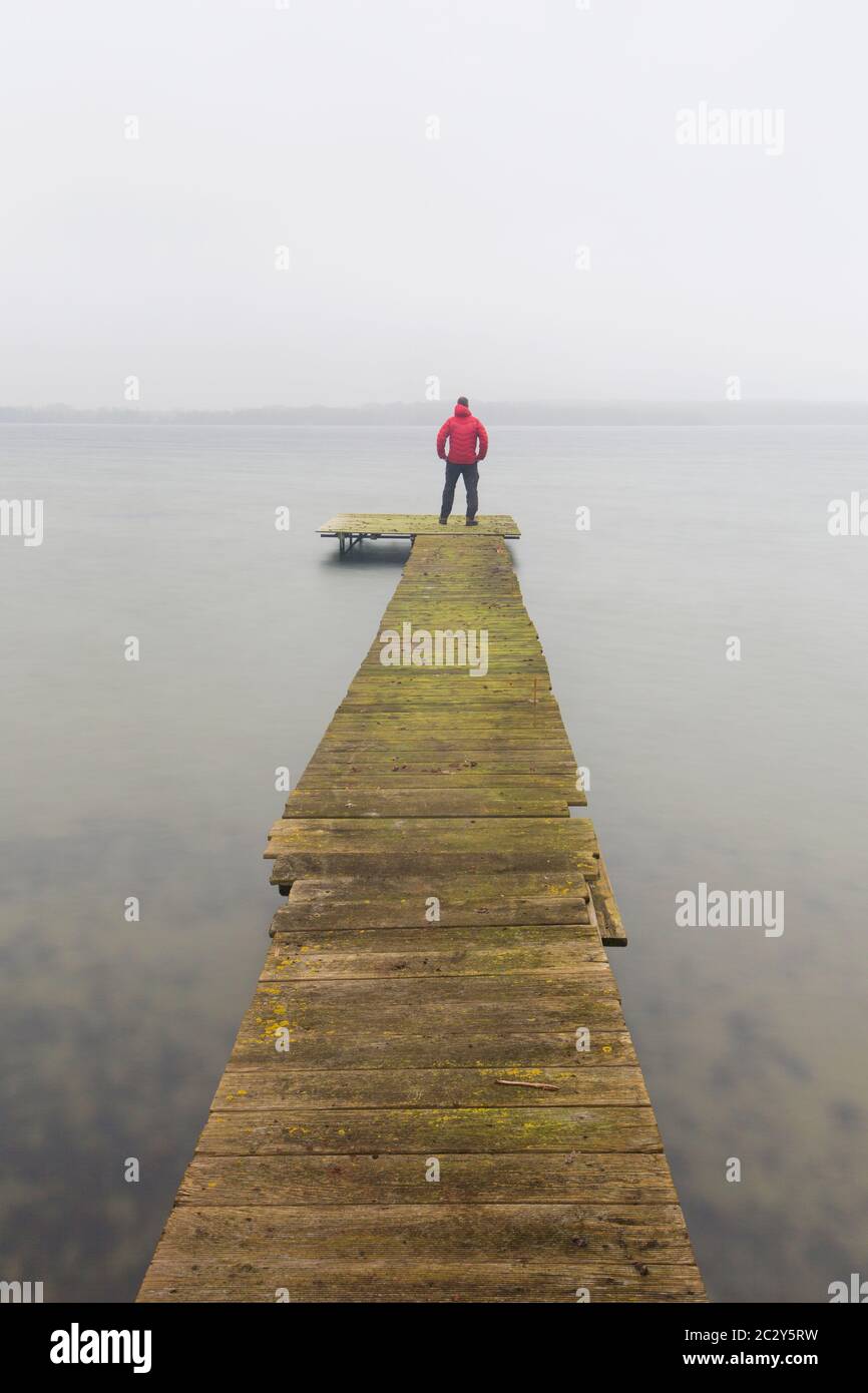 Mann auf Holzsteg am Großen Plöner See / Grosser Plöner See / Grosser Plöner See im Winter, Schleswig-Holstein, Deutschland Stockfoto