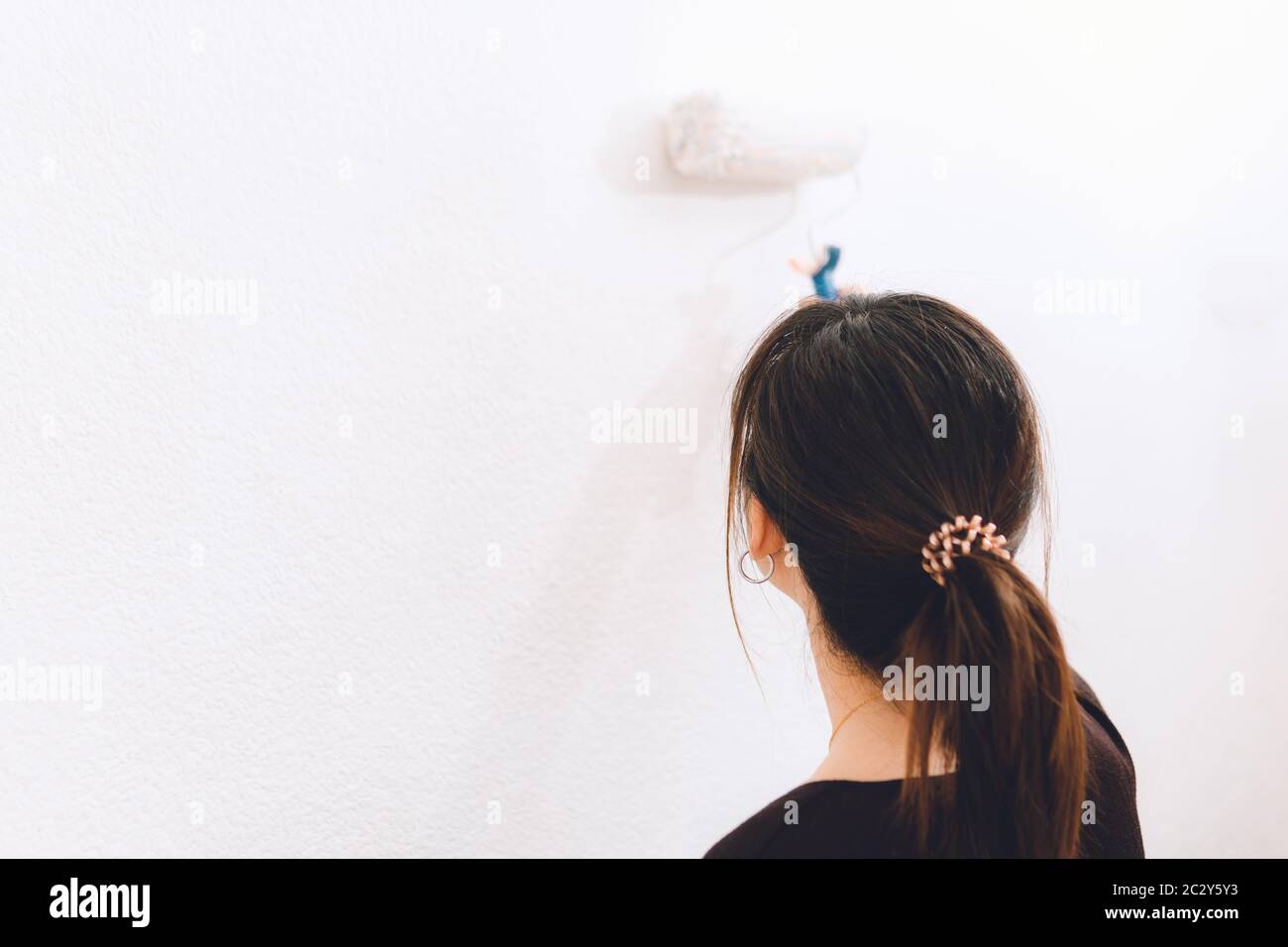 Junge Frau malt die Wand ihres Hauses weiß Stockfoto