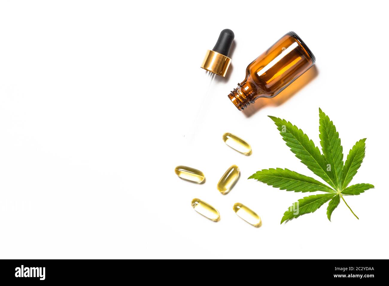 Cannabisöl, Pillen und grüne Blätter am weißen Tisch. Stockfoto