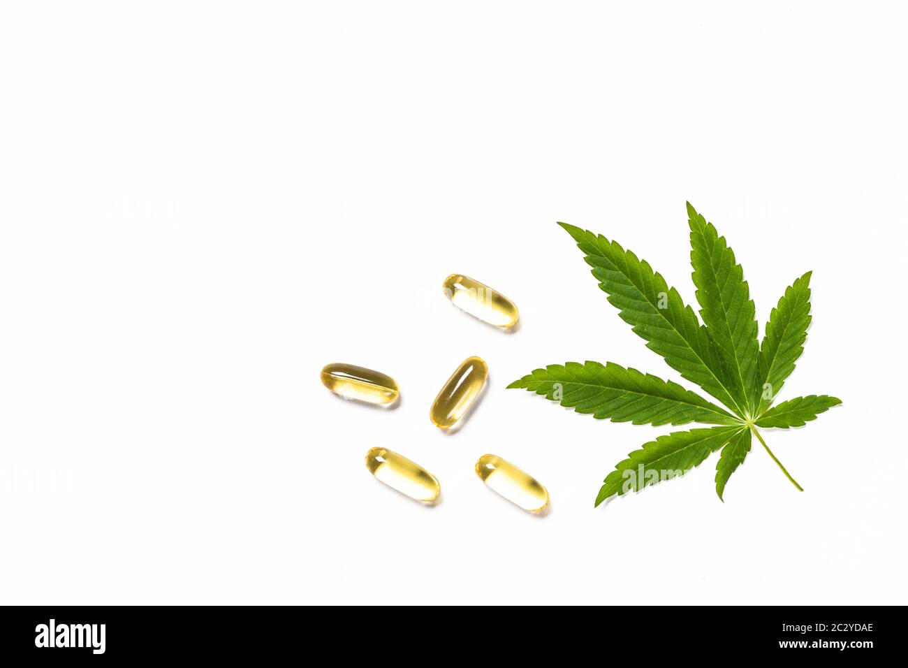 Cannabisöl, Pillen und grüne Blätter am weißen Tisch. Stockfoto