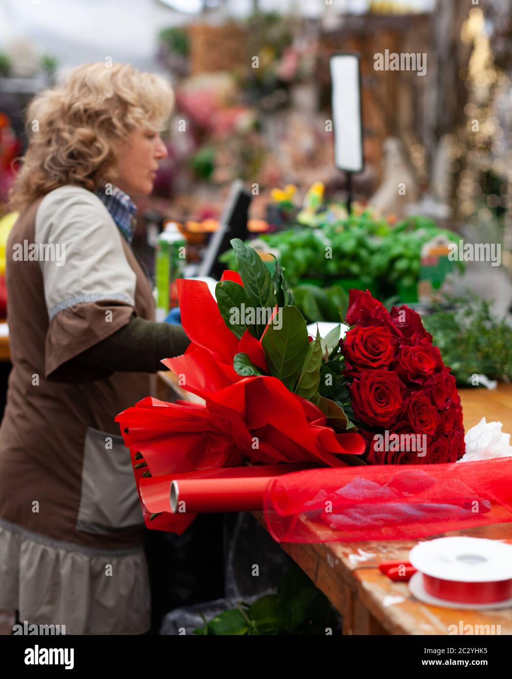 Blumengeschäft mit professionellen Kleidung in einer Baumschule. Vorbereitung eines Strauß roter Rosen. Stockfoto