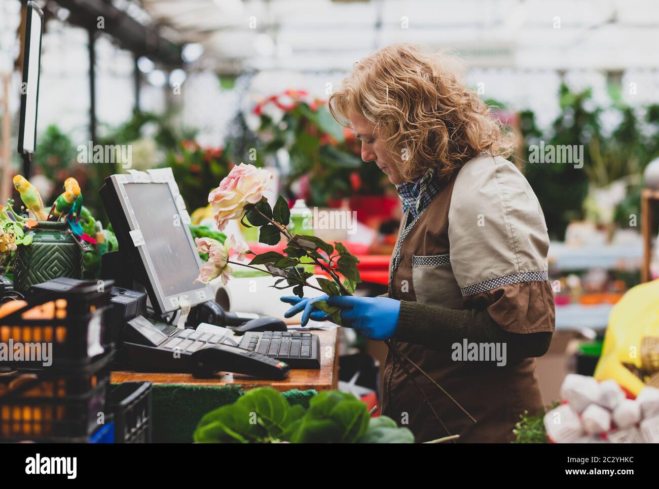 Blumengeschäft mit professionellen Kleidung in einer Baumschule. Konzept der elektronischen Bestellung und Zahlung. Stockfoto