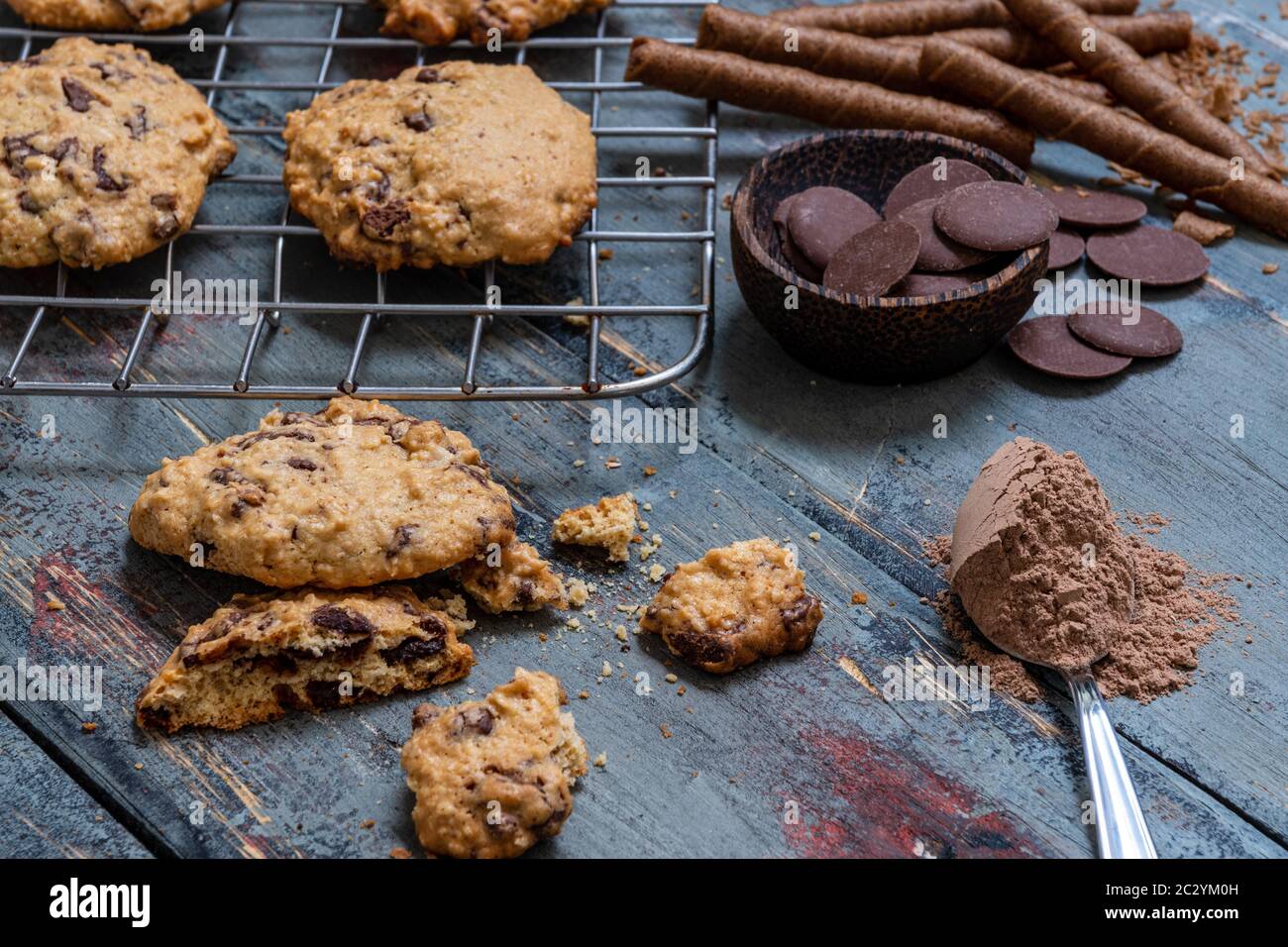 Schokoladenkuchen, auf rustikalem Holz neben Kakao in verschiedenen Formen Stockfoto