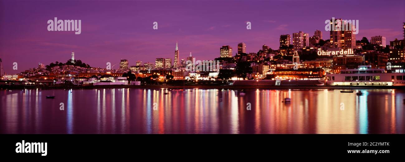 Boote vor dem beleuchteten Ghiradelli Square und umliegenden Gebäuden in der lila Dämmerung, San Francisco, Kalifornien, USA Stockfoto