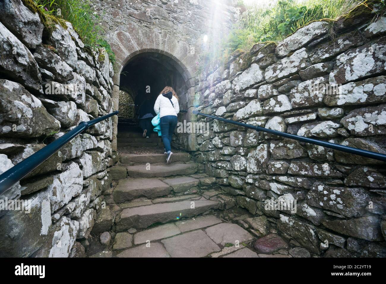 Zwei Leute, die an einer verlassenen Ruine eine alte Steintreppe hinauf zum Schloss Dunnottar in Schottland, Großbritannien, Europa, gehen Stockfoto