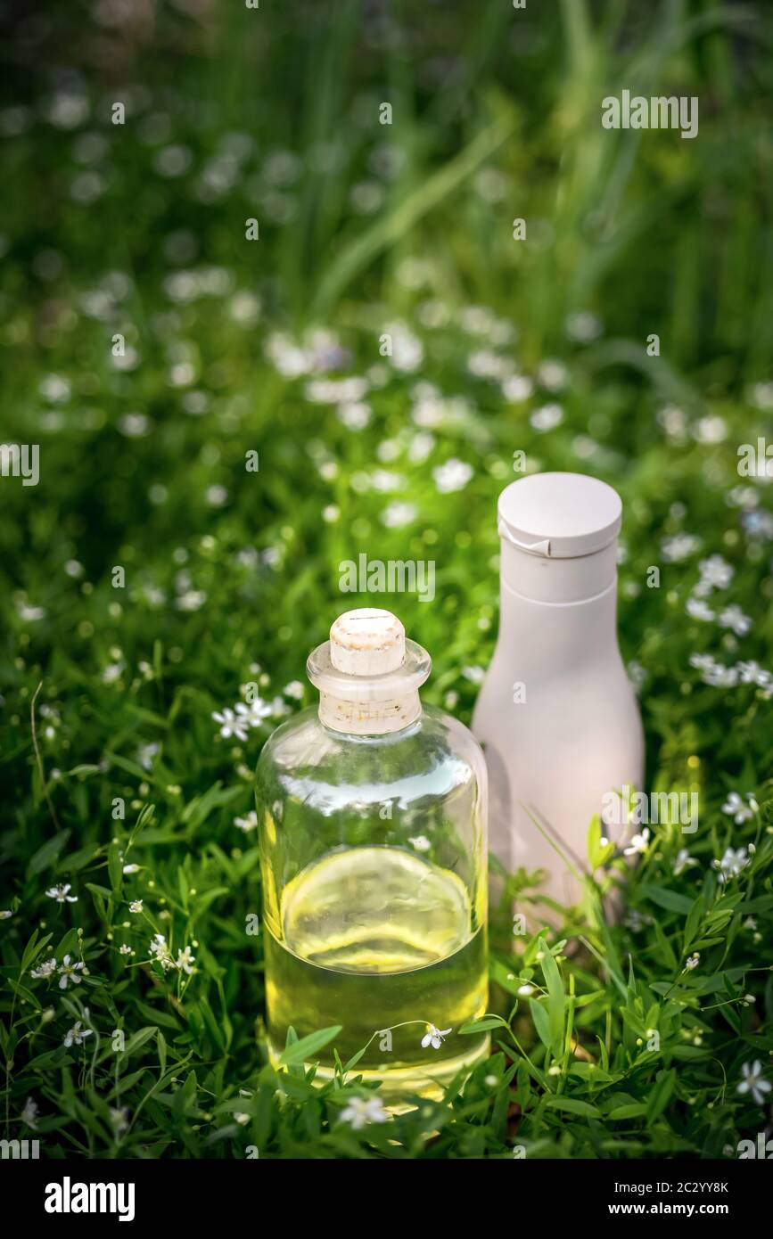 Natürliches Bio-Öl, Serum in der Flasche und Haar Shampoo auf grün grasigen Hintergrund Stockfoto