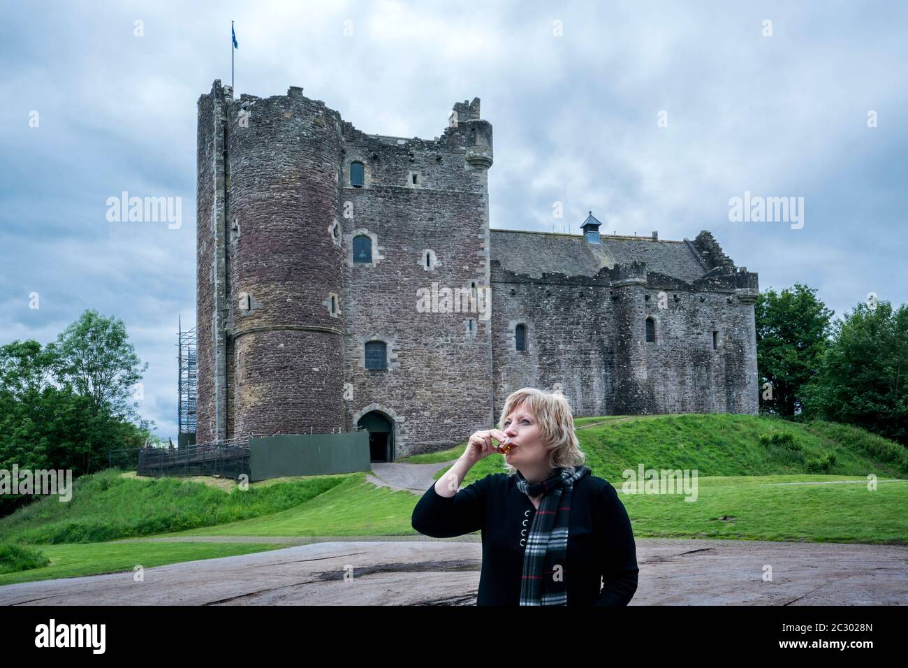 Blonde Touristen in ihren 50er Jahren trinkt einen Schluck Whisky draußen vor Doune Castle, Stirling, Schottland, Großbritannien, Europa Stockfoto