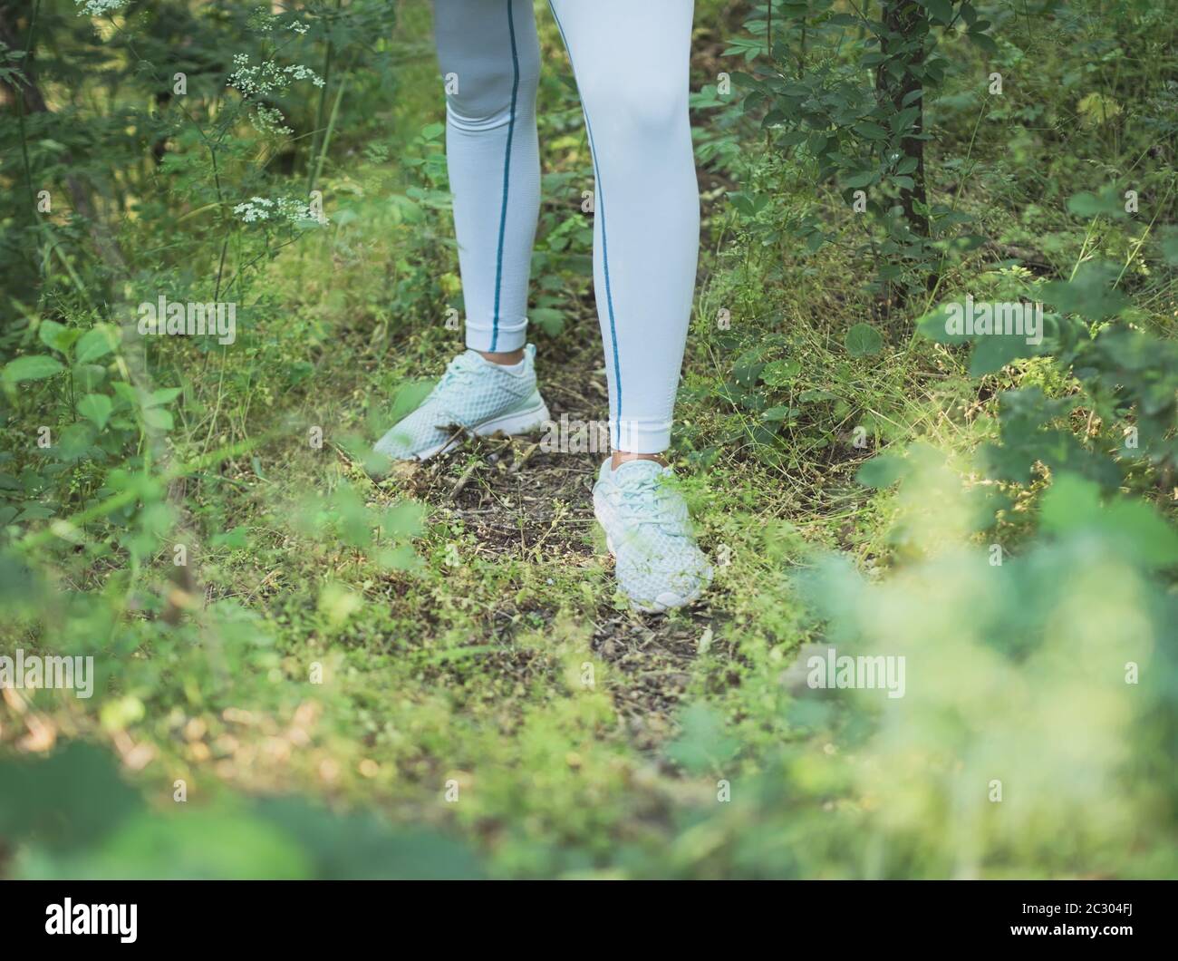 Weibliche Runner in Sportswear Stehen in dichten Wald Nahaufnahme auf Beinen Stockfoto