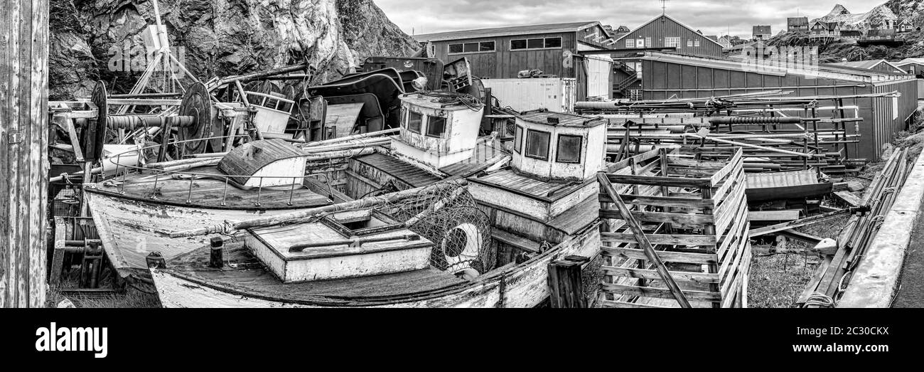 Zwei alte Fischerboote und Schutt liegen hinter Häusern im Dorf Sisimiut, Grönland Stockfoto