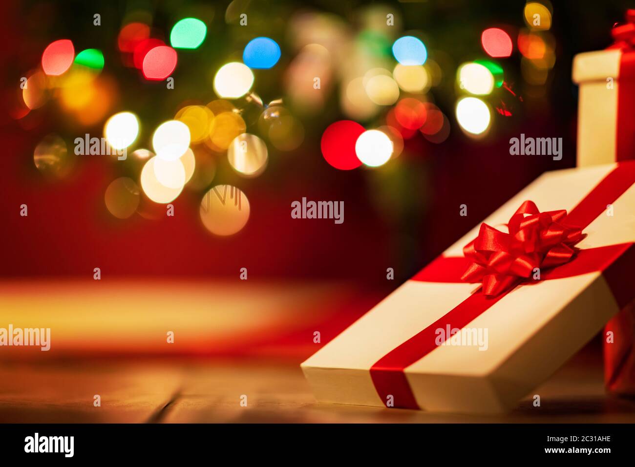 Geschenkboxen mit Band und Schleife auf Feiertagsbeleuchtung Hintergrund Stockfoto