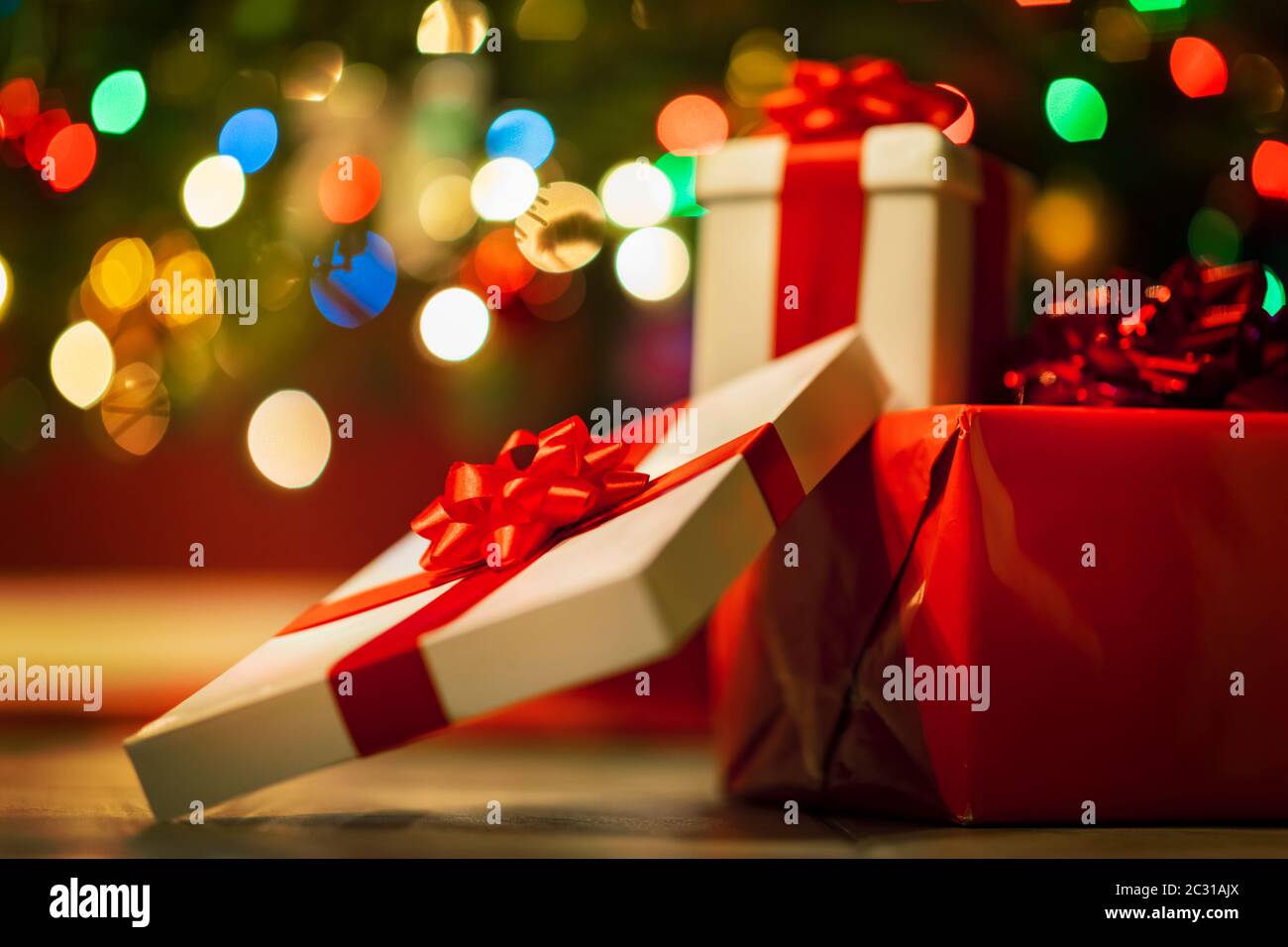 Geschenkboxen mit Band und Schleife auf Feiertagsbeleuchtung Hintergrund Stockfoto