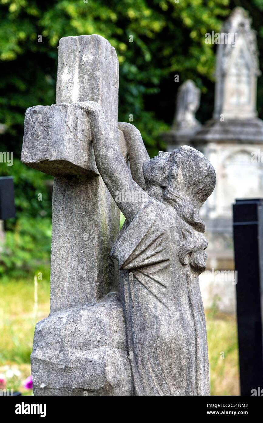 Grabmal einer trauernden Frau, die sich an einem Kreuz festklammert, Tower Hamlets Cemetery Park, London, Großbritannien Stockfoto