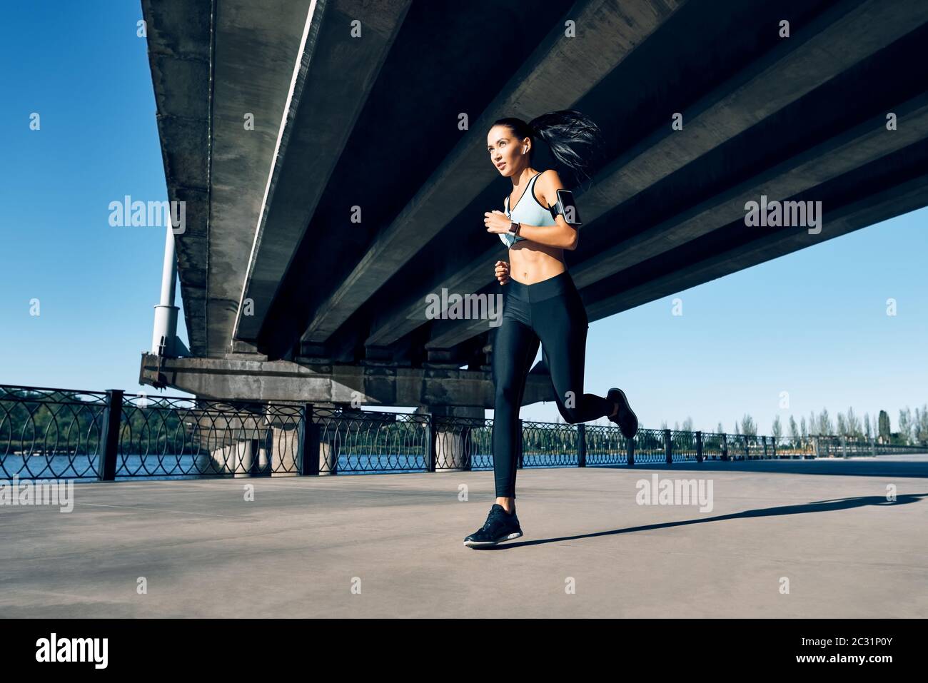 Junge Fitness-Frau läuft am Flussufer Stockfoto