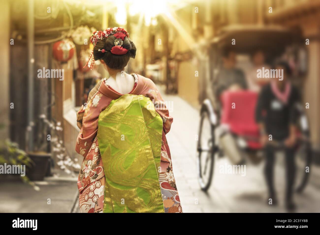 Maiko wandern in einer Gasse von Kyoto im Licht der untergehenden Sonne Überqueren einer Rikscha. Stockfoto