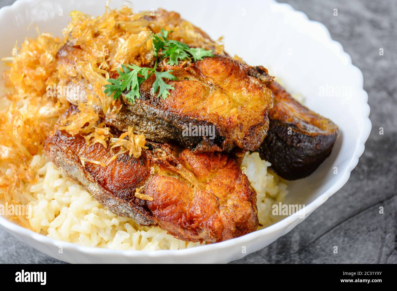 Frittierte scheiben Pangasius Fisch mit Knoblauch, mit braunem Reis serviert. Stockfoto