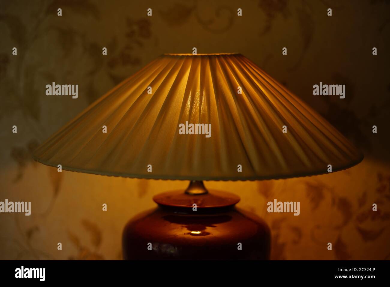 Faltenlampenschirm mit warmem Licht im dunklen Raum, Nahaufnahme. Stockfoto
