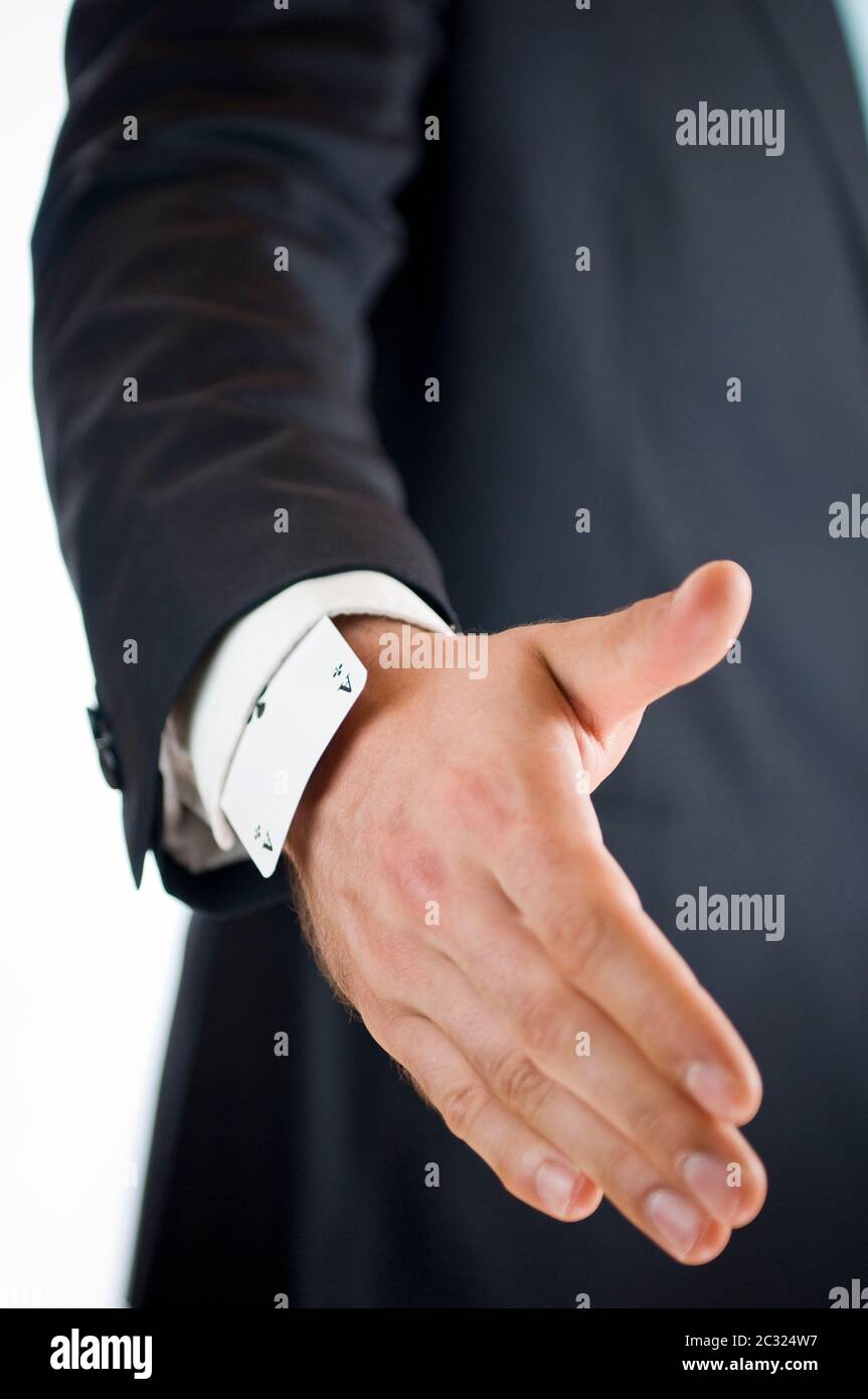 Nahaufnahme der rechten Hand eines männlichen Menschen in einer Farbe mit einem Ass, das die Karte auf dem Ärmel spielt, ausgestreckt zur Kamera, gegen einen weißen Hintern Stockfoto