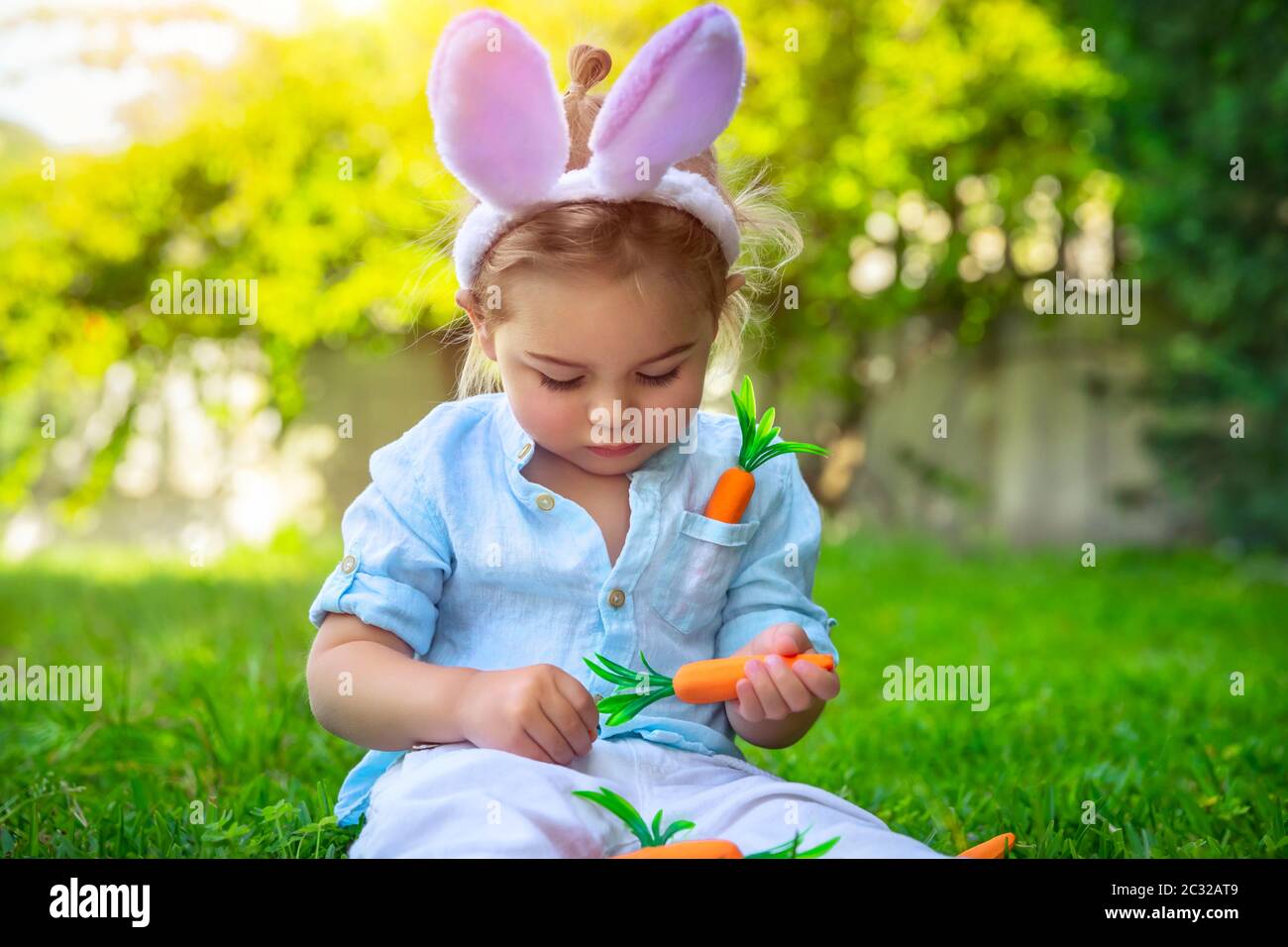 Porträt eines entzückenden kleinen Jungen trägt Hasenohren, spielen mit dekorativen Karotten - traditionelle Osterkost, Kind genießen glücklichen Frühling Chri Stockfoto