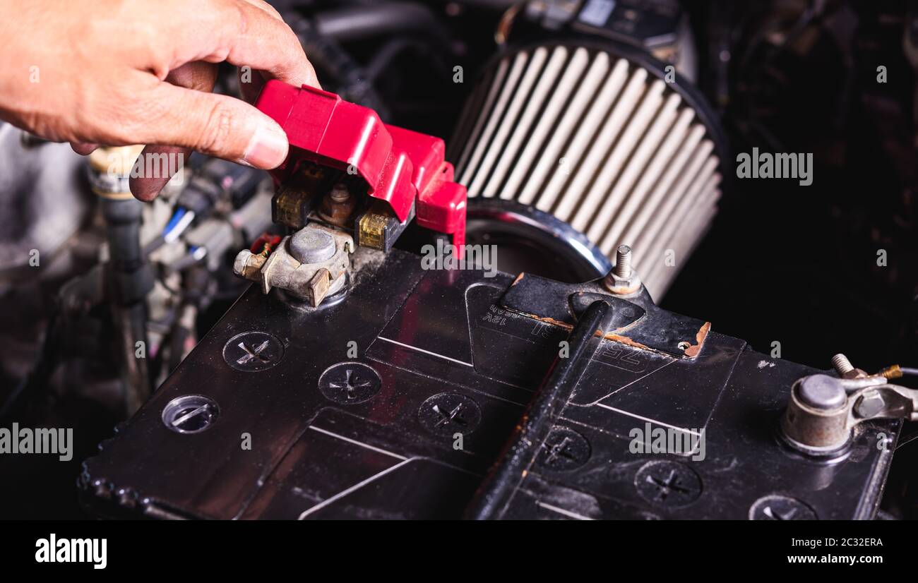 Hand des Techniker Service überprüfen Sie die Batteriespannung und schalten Sie die Batterie Schraube lose in einer Garage. Stockfoto